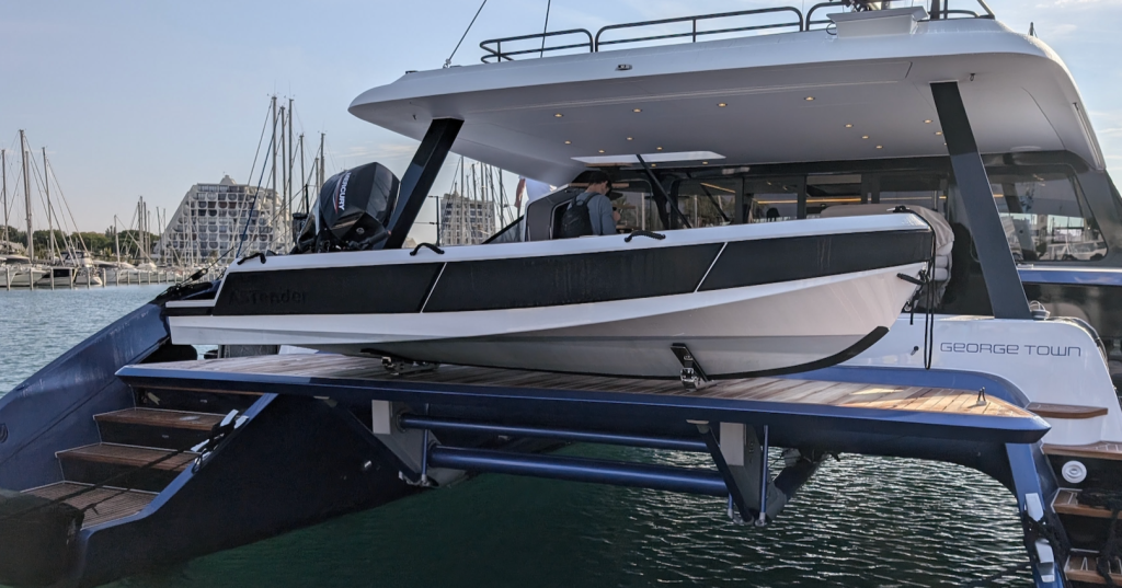White luxury motor yacht named 'George Town' on a blue hydraulic lift at a marina, with steps and water visible nearby.
